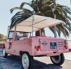 a pink jeep parked on the street with palm trees in the backgrouund