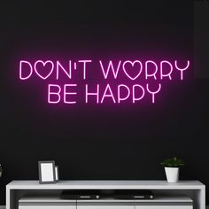 a neon sign that says don't worry be happy on the side of a wall