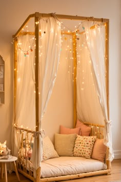 a canopy bed with white curtains and lights on the ceiling is in a child's room