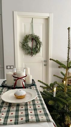 a white plate topped with a frosted donut next to a green christmas tree