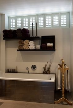 a bath room with a tub and shelves filled with towels