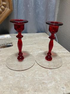 two red glass candlesticks sitting on top of a table