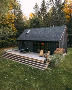 a small cabin in the woods with steps leading up to it's patio area