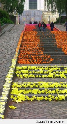 people are walking up and down the stairs decorated with yellow paper flowers in front of a building