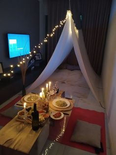 a table with food and candles on it in front of a television set up for a party