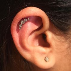 a woman's ear with three small diamond studs