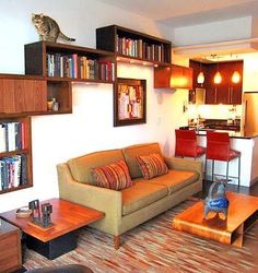 a living room filled with furniture and a cat statue on top of a book shelf