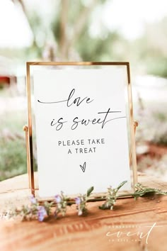 a sign that says love is sweet please take a treat on top of a wooden table