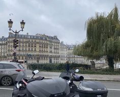 two motorcycles are parked on the side of the road in front of an old building