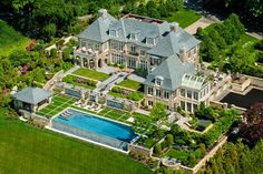 an aerial view of a large mansion with a swimming pool in the middle of it