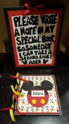 a mickey mouse notebook with a red ribbon tied to it and a sign that says please write a note in my special box