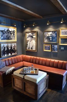 a corner booth with leather seats and pictures on the wall