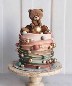 a teddy bear sitting on top of a multi layered cake