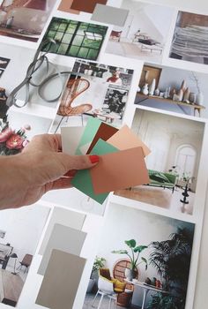 a person is holding some paper and scissors in front of many pictures on the wall