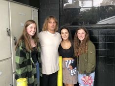 three girls and a man standing in front of a locker with their arms around each other