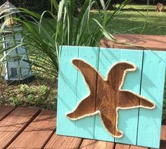 a wooden sign with a bird painted on it's side sitting on a deck