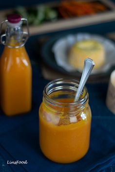 two jars filled with orange sauce sitting on top of a blue table covered in food