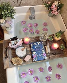 a bath tub filled with flowers and candles next to a book on top of it