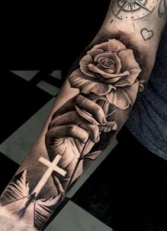 a black and white rose with a cross tattoo on the left arm, in front of a checkered floor