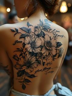 the back of a woman's body with flowers on it and words written in cursive writing