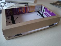 an open cardboard box sitting on top of a desk with several books in the bottom