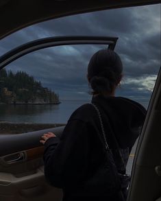 a woman sitting in the passenger seat of a car looking out at an island and water