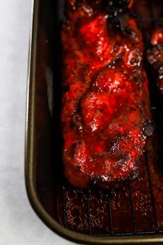 two pieces of meat cooking on top of an oven rack in a baking pan,