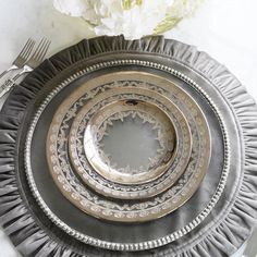 three silver plates on a marble table with flowers in the center and two forks next to them