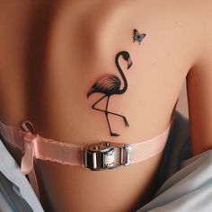 a flamingo tattoo on the back of a woman's body, with a butterfly flying above it