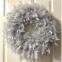 a white door with a gray feather wreath on it