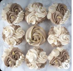 cupcakes decorated with white and brown icing on a marble table top next to each other