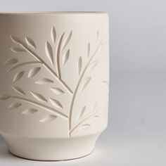 a white vase with leaves carved on it