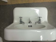 a white sink with two faucets on it