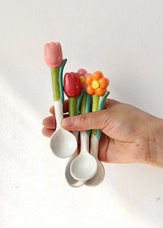 a hand holding three spoons with flowers in them