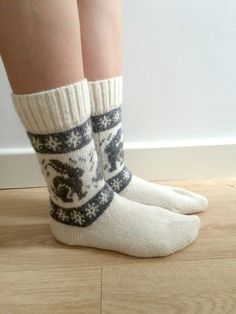 the legs of a person wearing socks with snowflakes on them, standing on a wooden floor