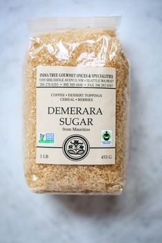 a bag of demerara sugar sitting on top of a white countertop next to a bottle of liquid