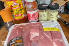 raw meat and spices on a table with utensils, seasonings, and sauces