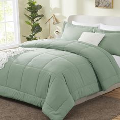 a bed with green comforter and white pillows