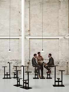 three men sitting at a table in an industrial building