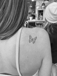 a woman with a small butterfly tattoo on her upper back shoulder and arm, in black and white