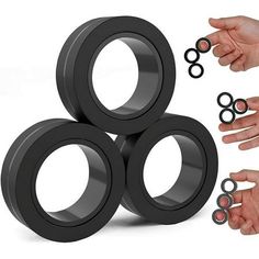 four black rings are being held by two hands