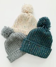 three knitted hats with pom - poms