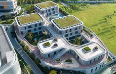 an aerial view of a building with green roofing on the top and two buildings below