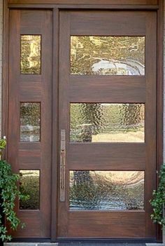 a close up of a wooden door with two planters on either side and one window