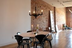 a dining room with brick walls and wooden flooring is seen in this image, there are several chairs around the table