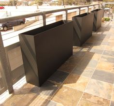 three metal planters sitting on the side of a building