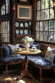 a table with two chairs and a vase on it sitting in front of a window