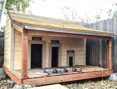 a dog house made out of pallets with bowls on the outside and doors open