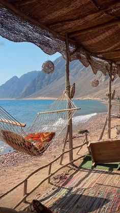 a hammock hanging from the side of a wooden structure next to the ocean