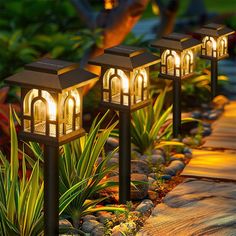 three lights that are sitting in the grass next to some rocks and plants on the ground